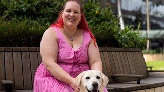 A person sitting with their Guide Dog.