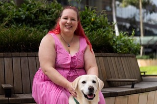 A person sitting with their Guide Dog.