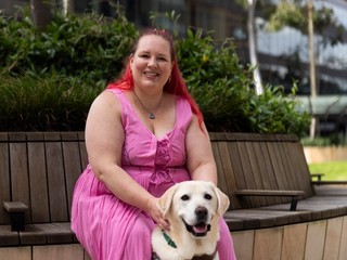 A person sitting with their Guide Dog.