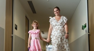 Ivy walking with her mother and smiling at the camera.