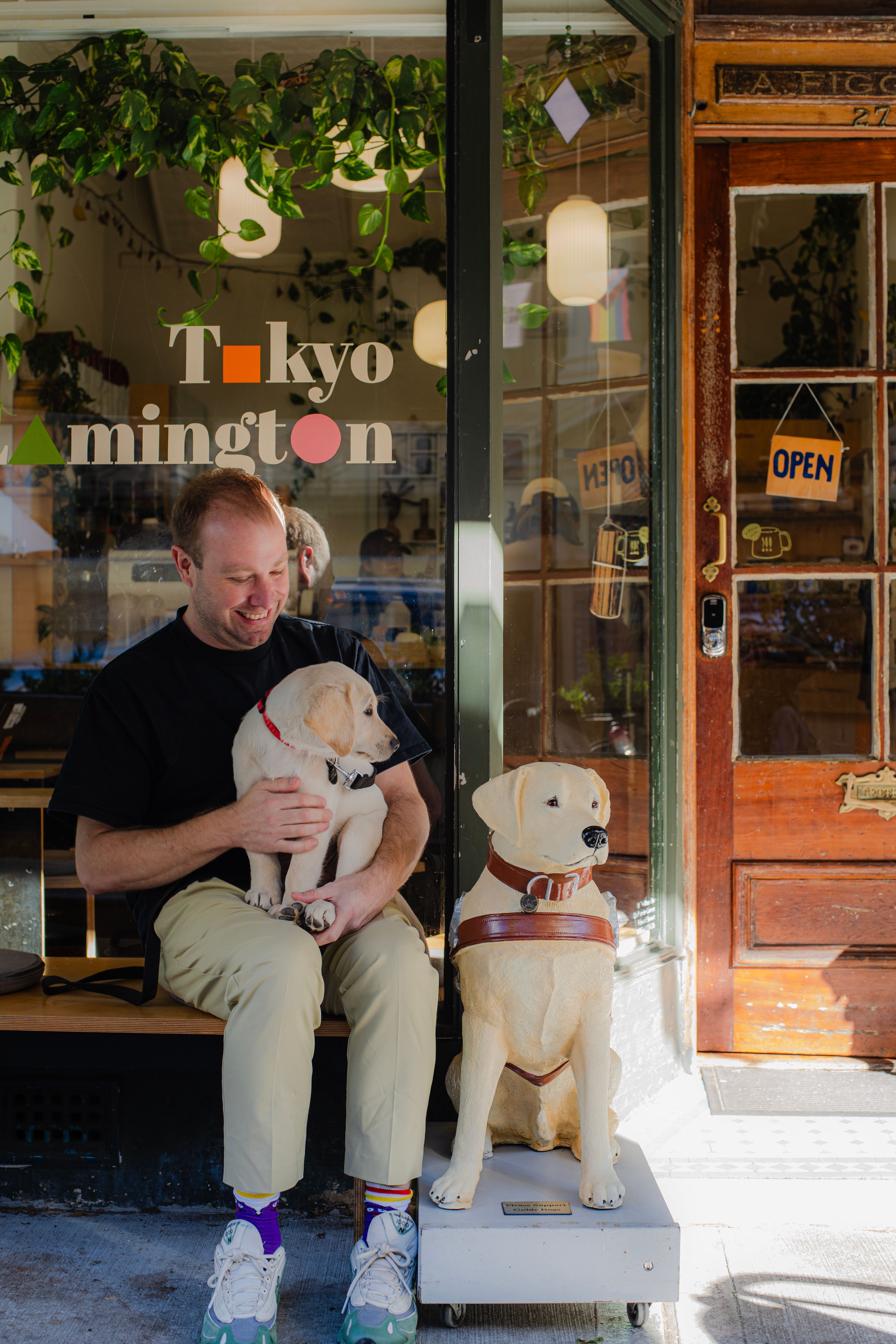 A person holding a puppy next to a donation dog.