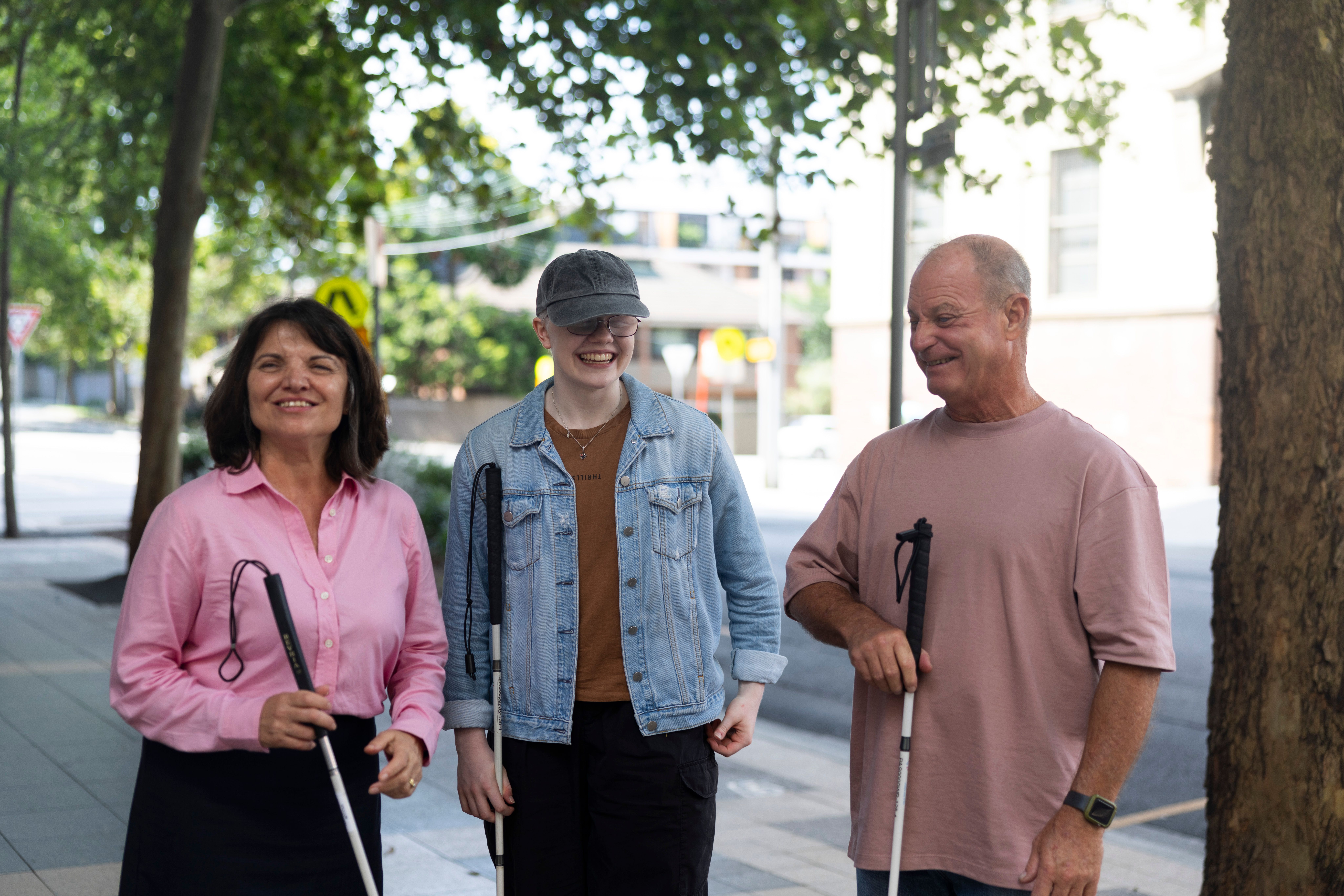 Three Clients standing with their white canes smiling.