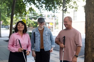 Three Clients standing and smiling with their white canes.
