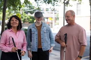 Three Clients with their white canes standing together smiling.