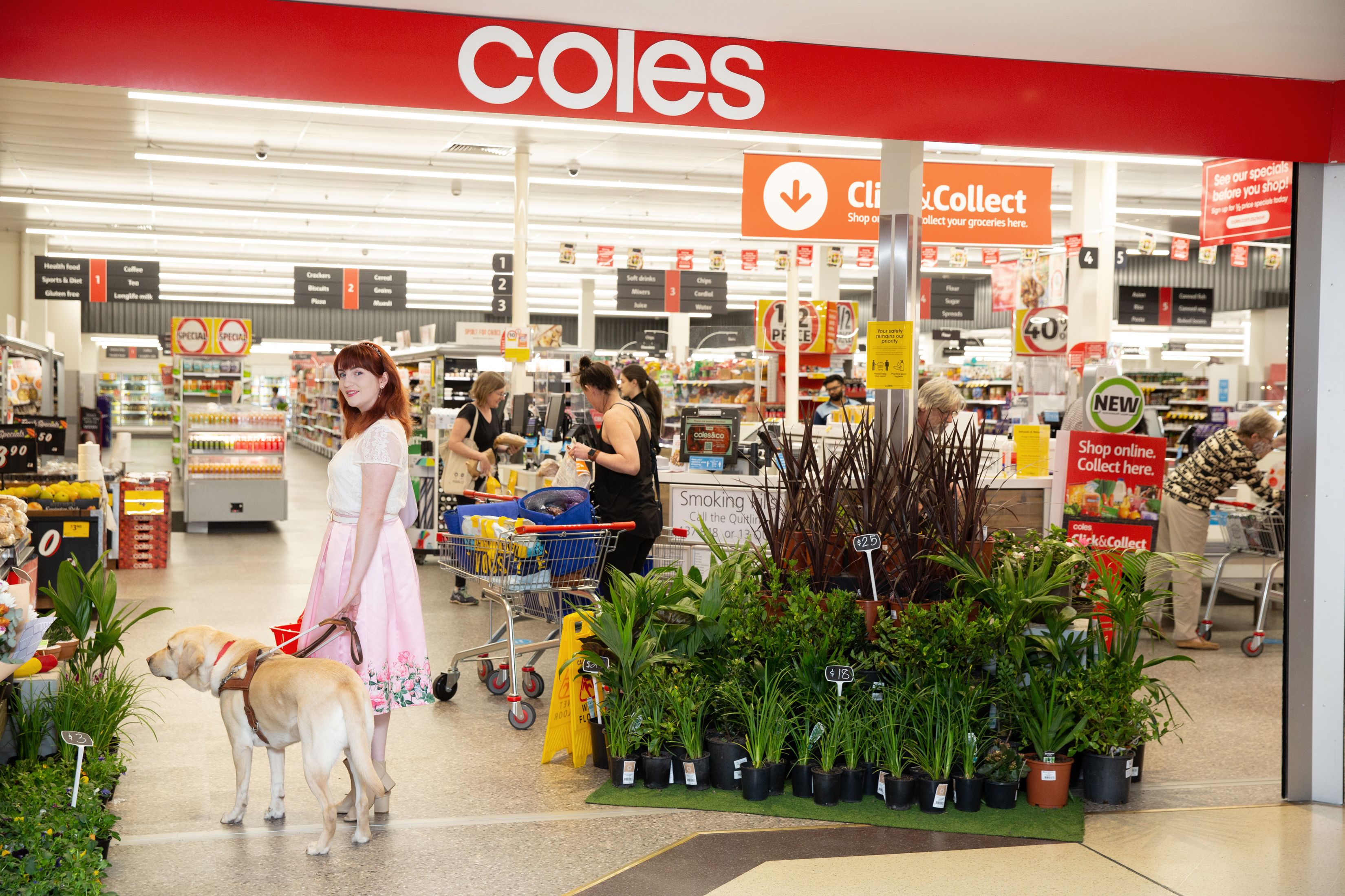 Ingrid standing outside a Coles with her Guide Dog Banner.