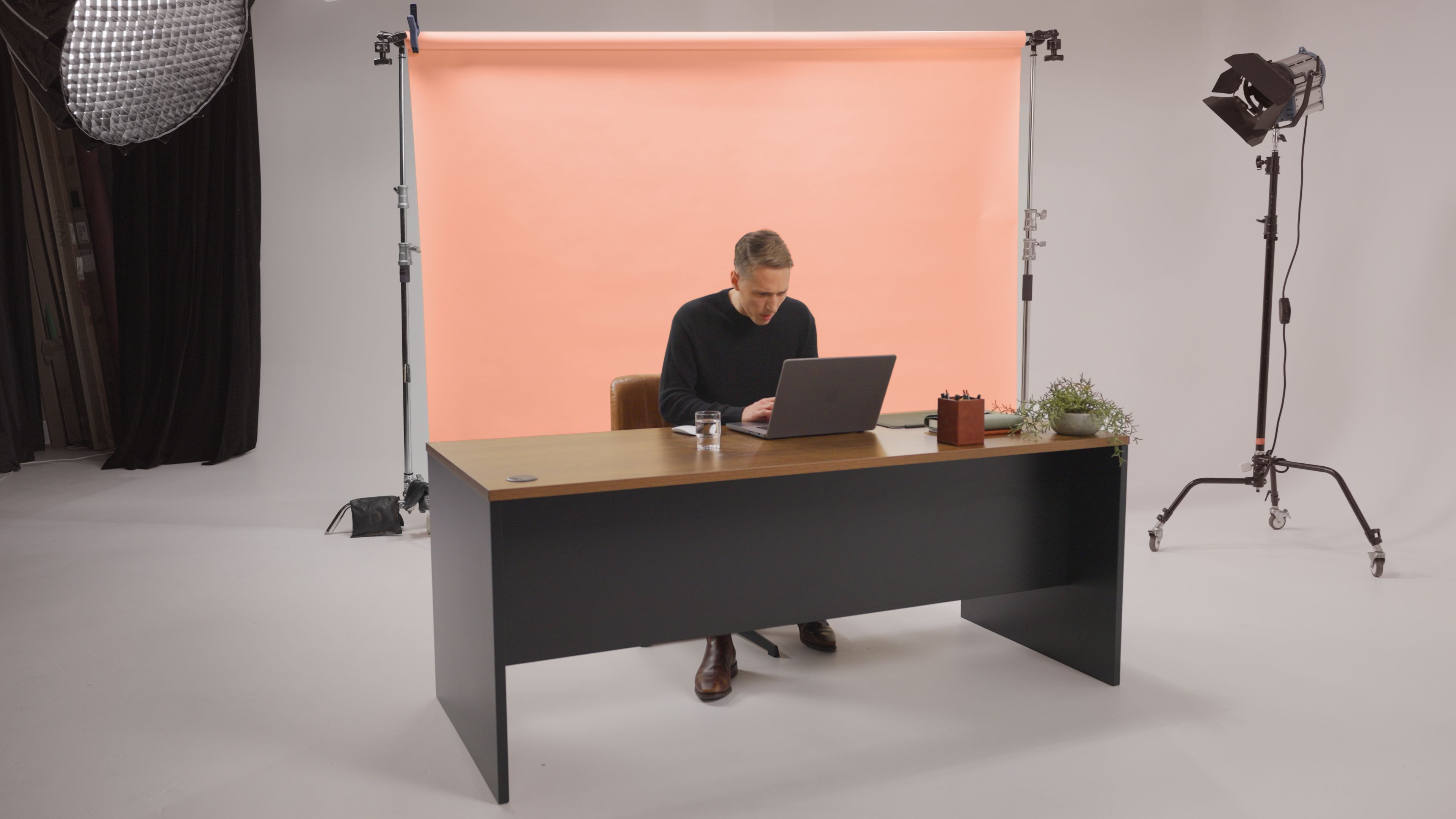 A man sitting at a desk with a laptop in front of him.