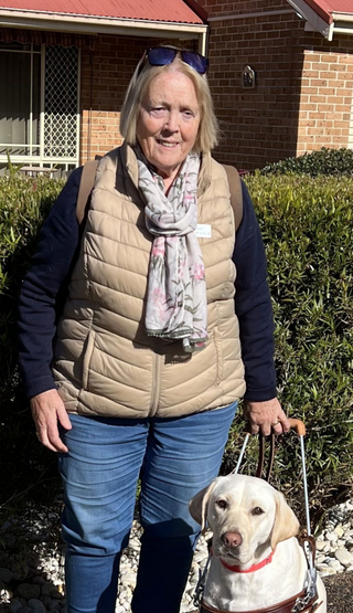 Angela standing with her yellow Labrador Guide Dog.