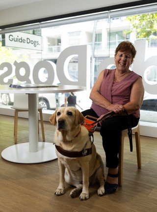 A Handler sitting with her yellow Guide Dog.