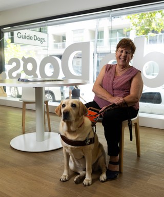 A Handler sitting with her yellow Guide Dog.