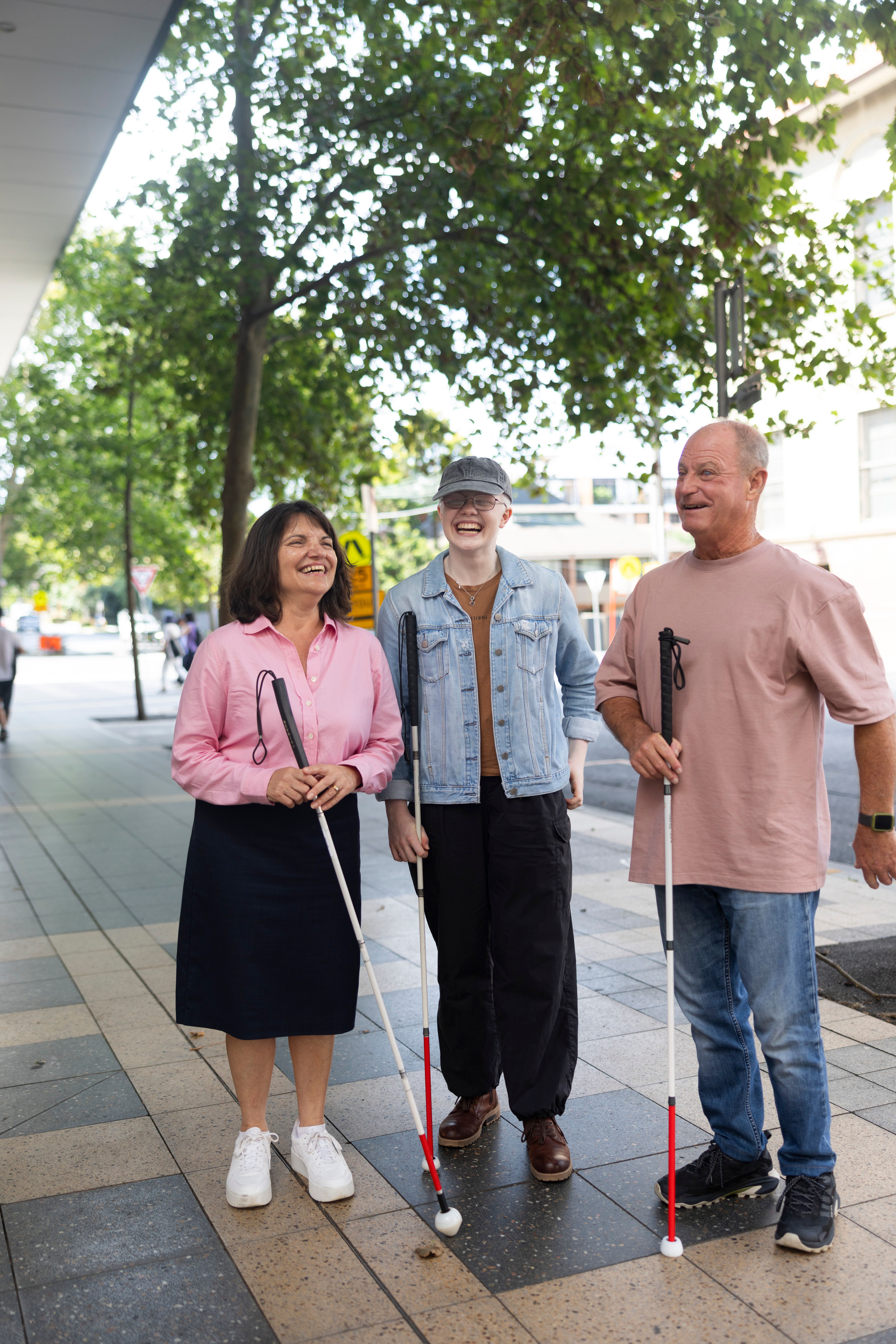 Three Clients standing together with their White Canes and smiling.
