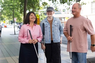 Three Clients standing together with their White Canes and smiling.