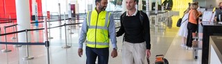 Airport staff member guiding a Guide Dog Handler.