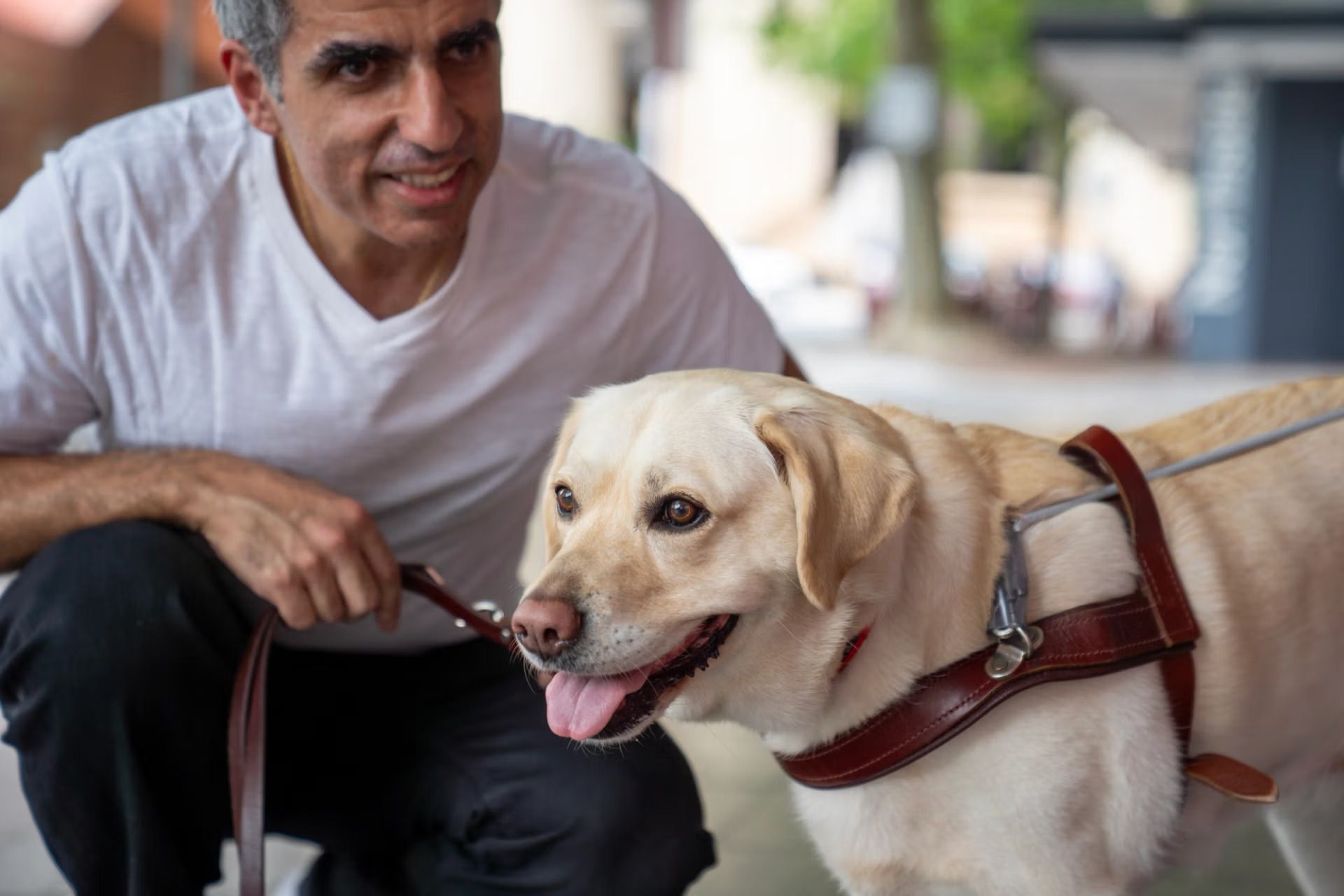A Guide Dog Handler kneeling next to their Guide Dog.