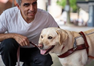 A Guide Dog Handler kneeling next to their Guide Dog.