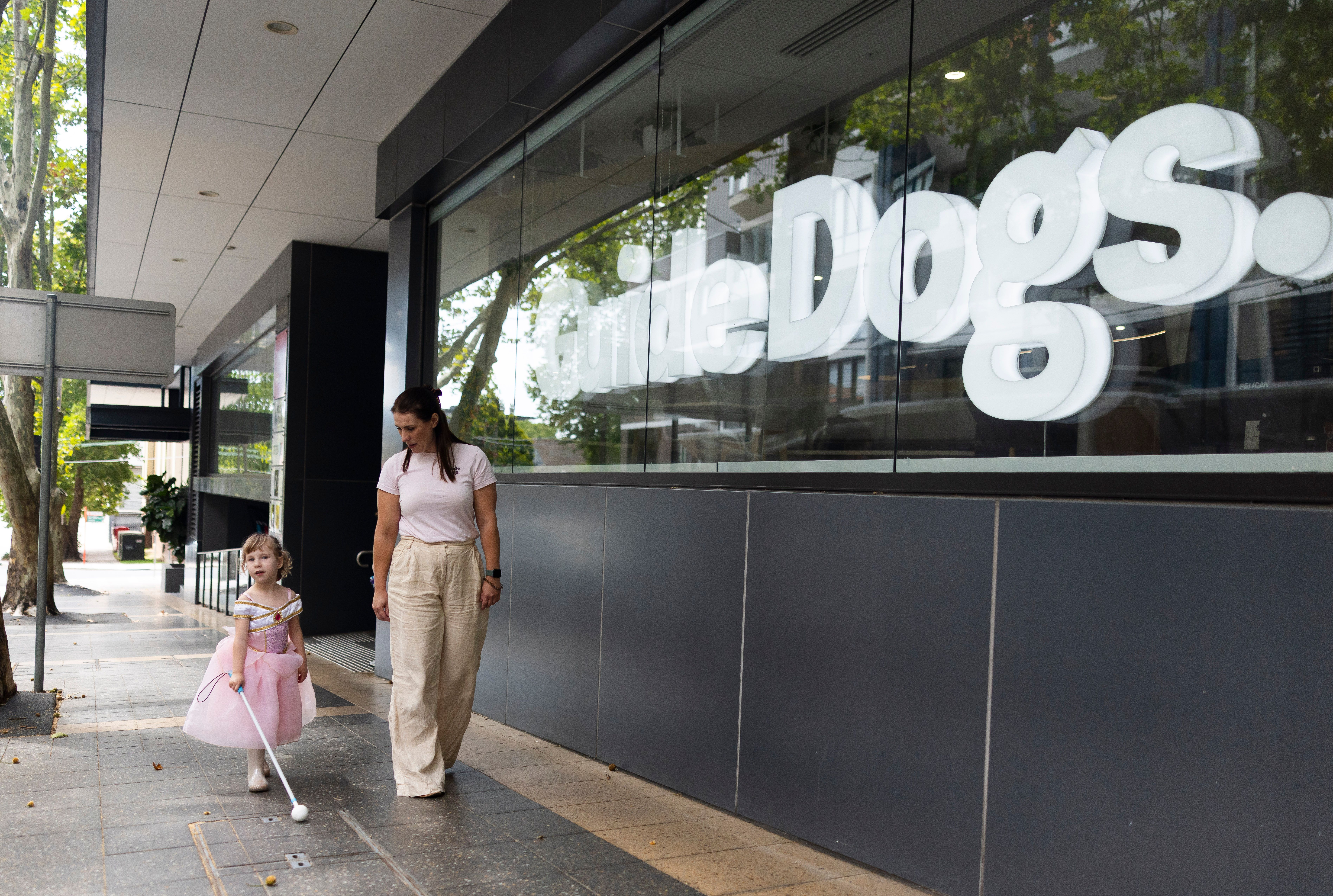 A staff member walking with a Client and their cane.