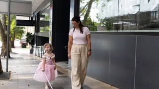 A staff member walking with a Client and their cane.