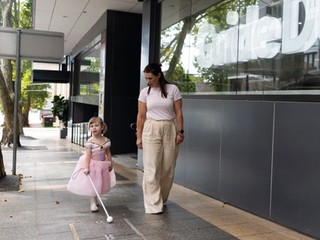 A staff member walking with a Client and their cane.