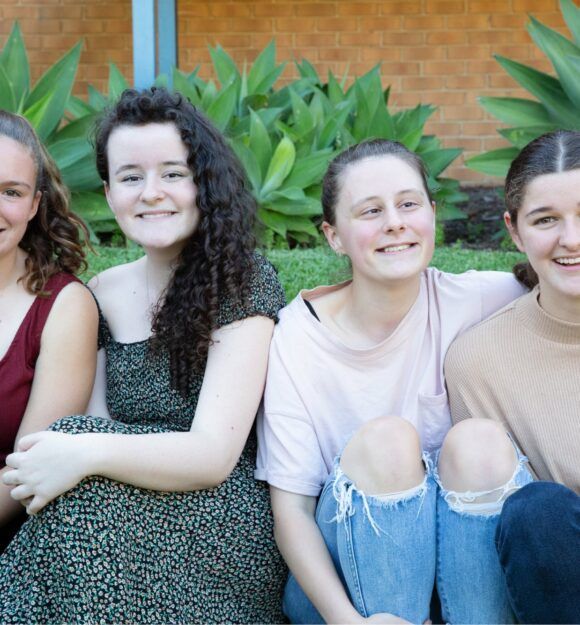 Four teenage girls sitting together outside.