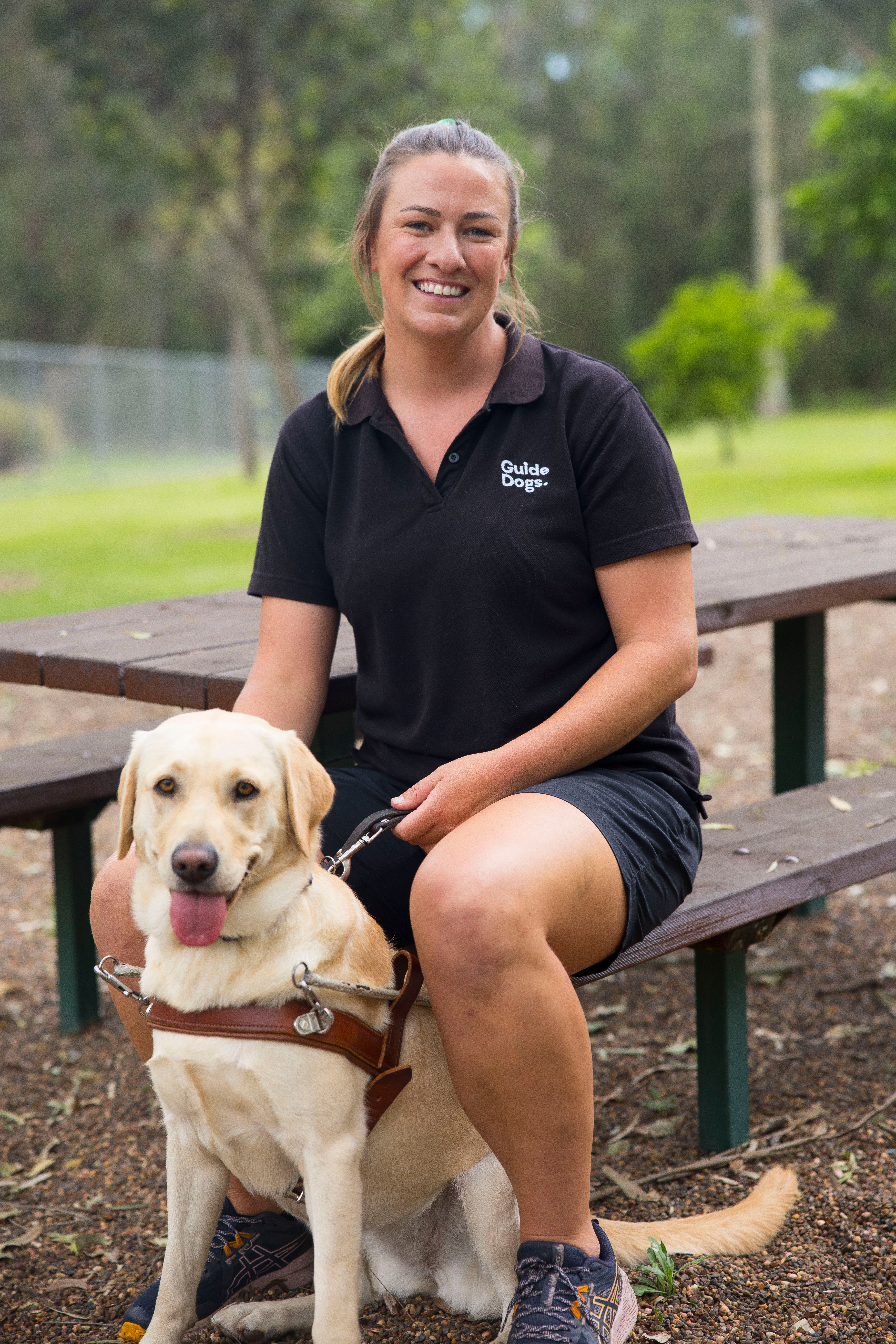 A Guide Dog trainer sitting with a Dog.