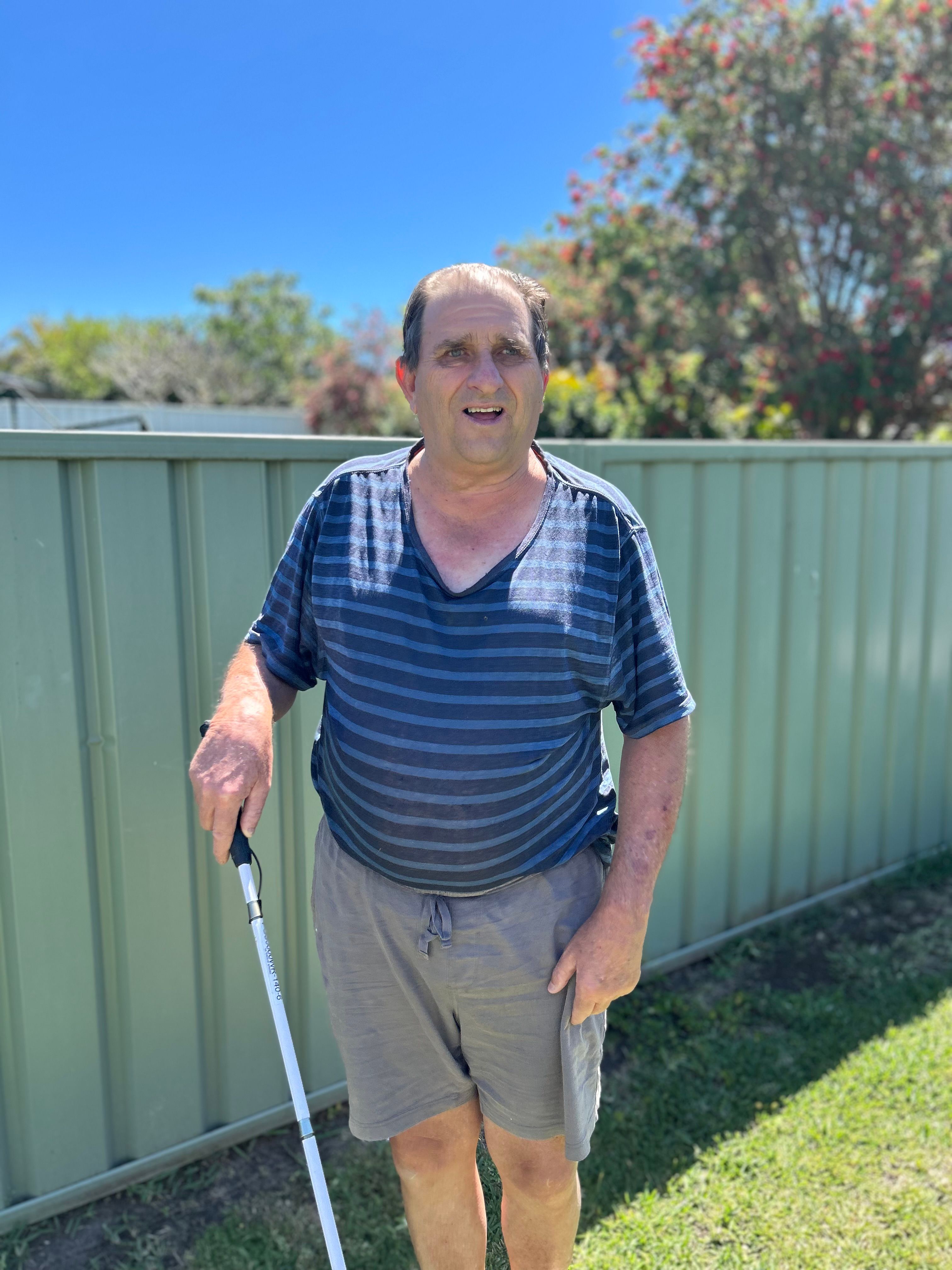 Bevan standing outside and holding a white cane.
