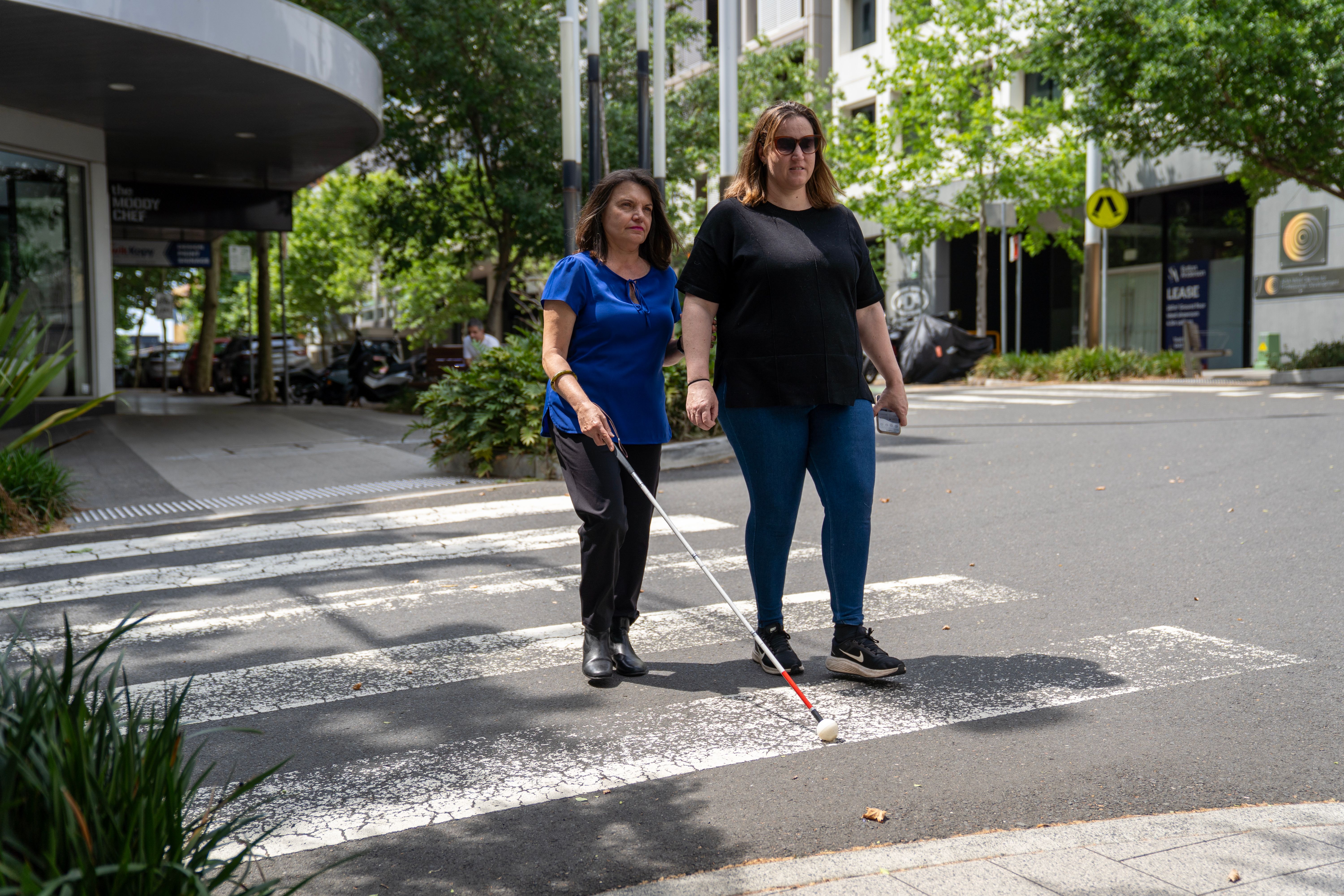 A person guiding another across a pedestrian crossing.