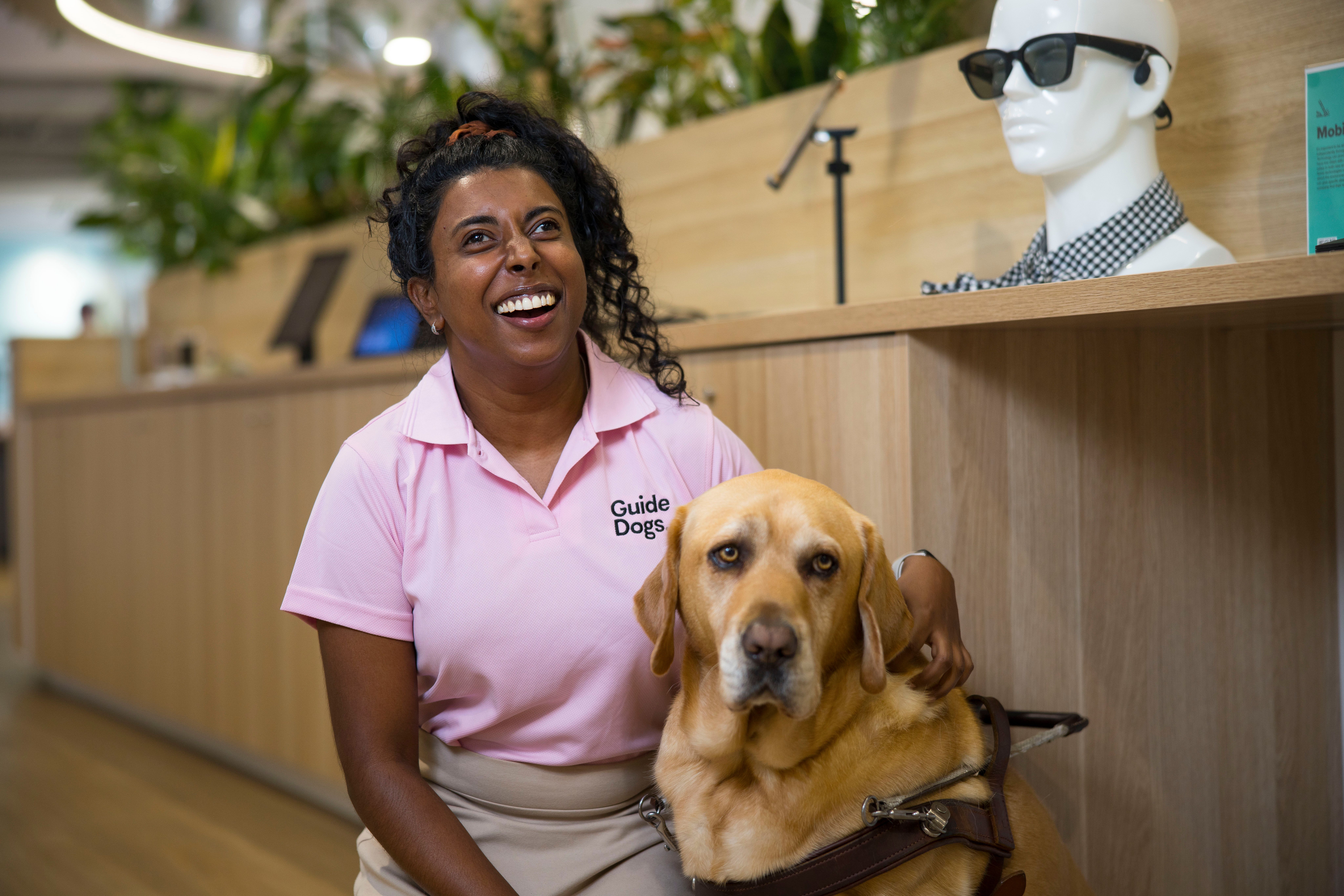 Abby sitting with her Guide Dog Duke and smiling.