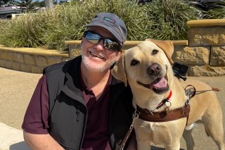 A Guide Dog Handler smiling with their Guide Dog.