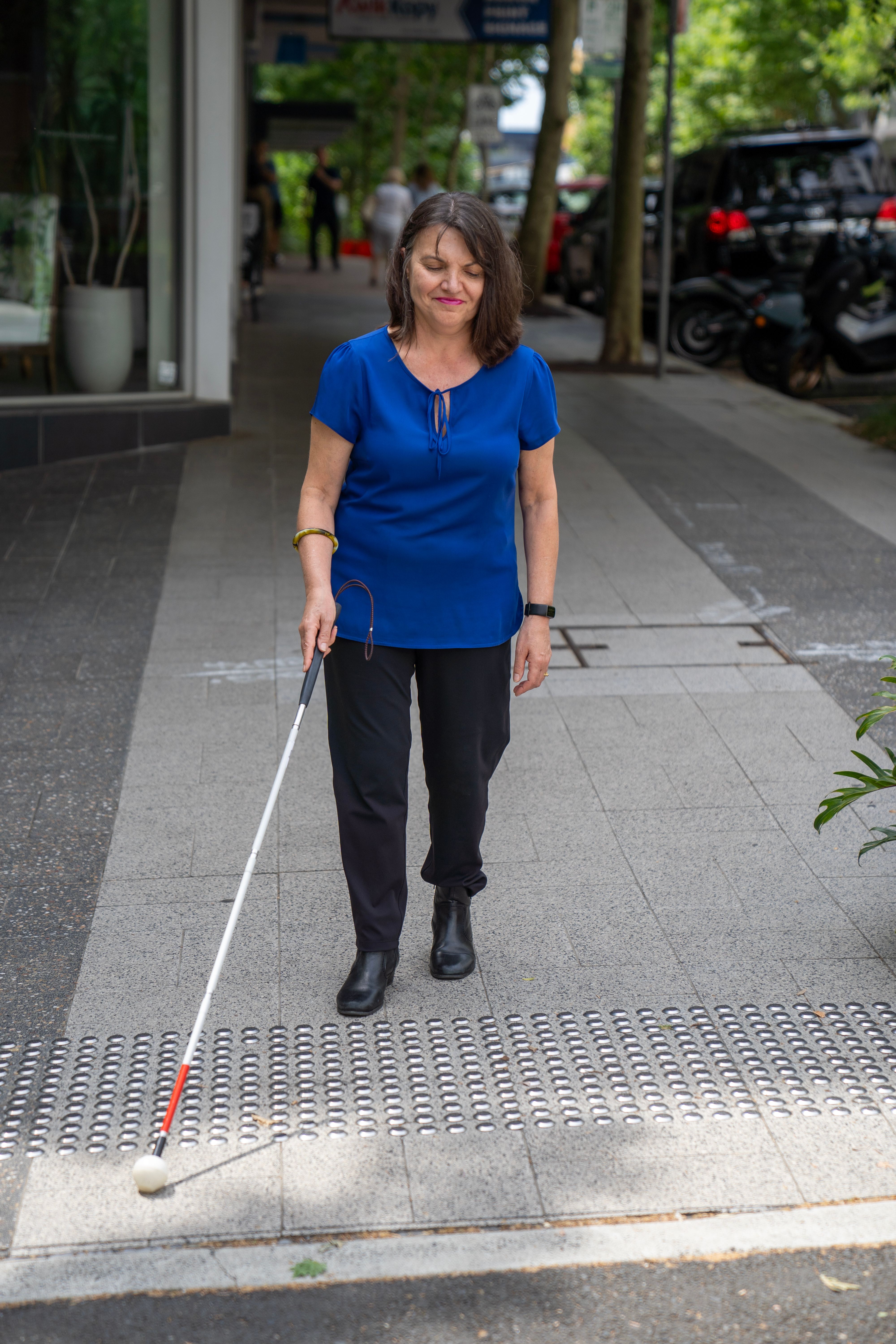 A person using tactile markers at a crossing.