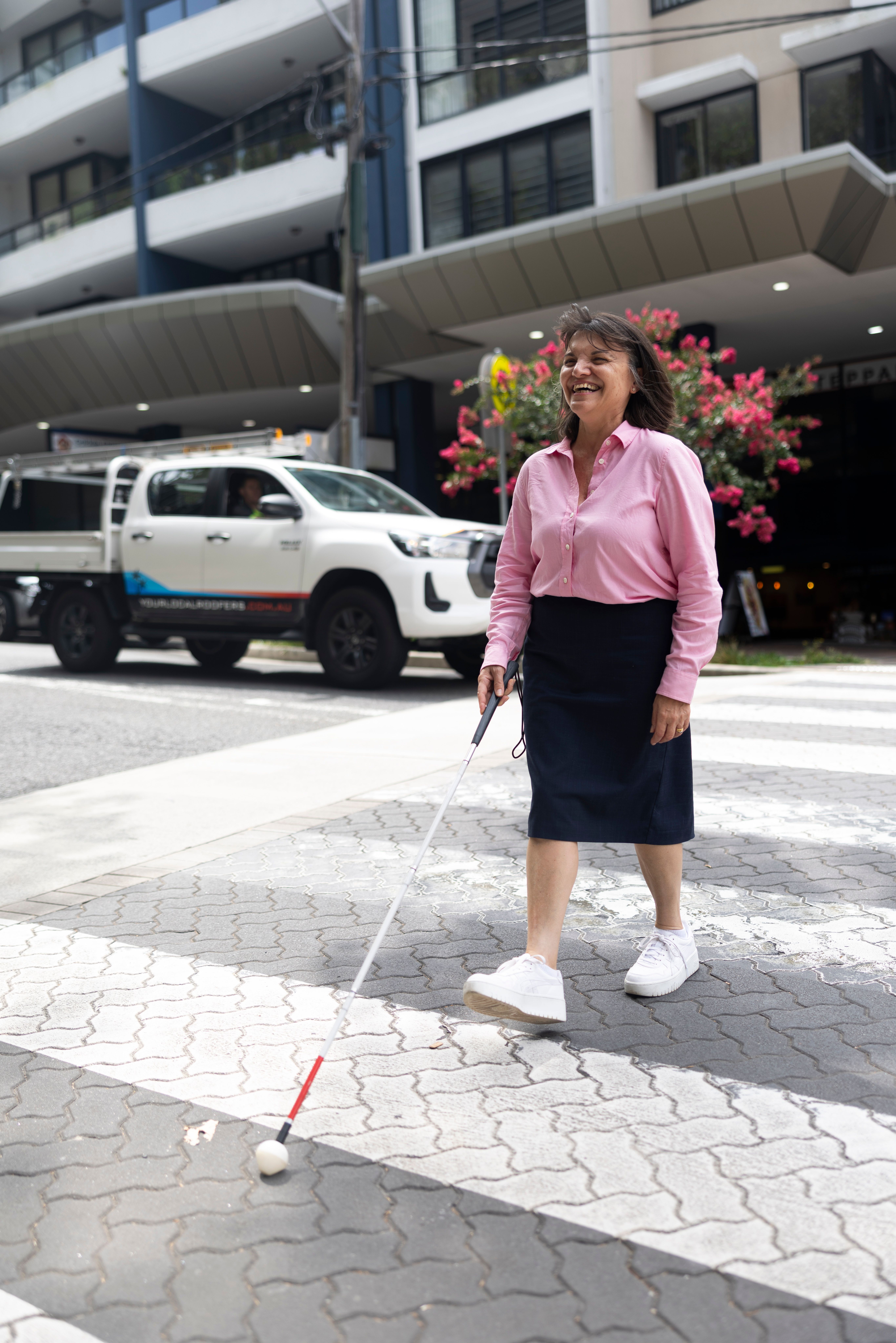 A Person walking with their cane across the pedestrian crossing.