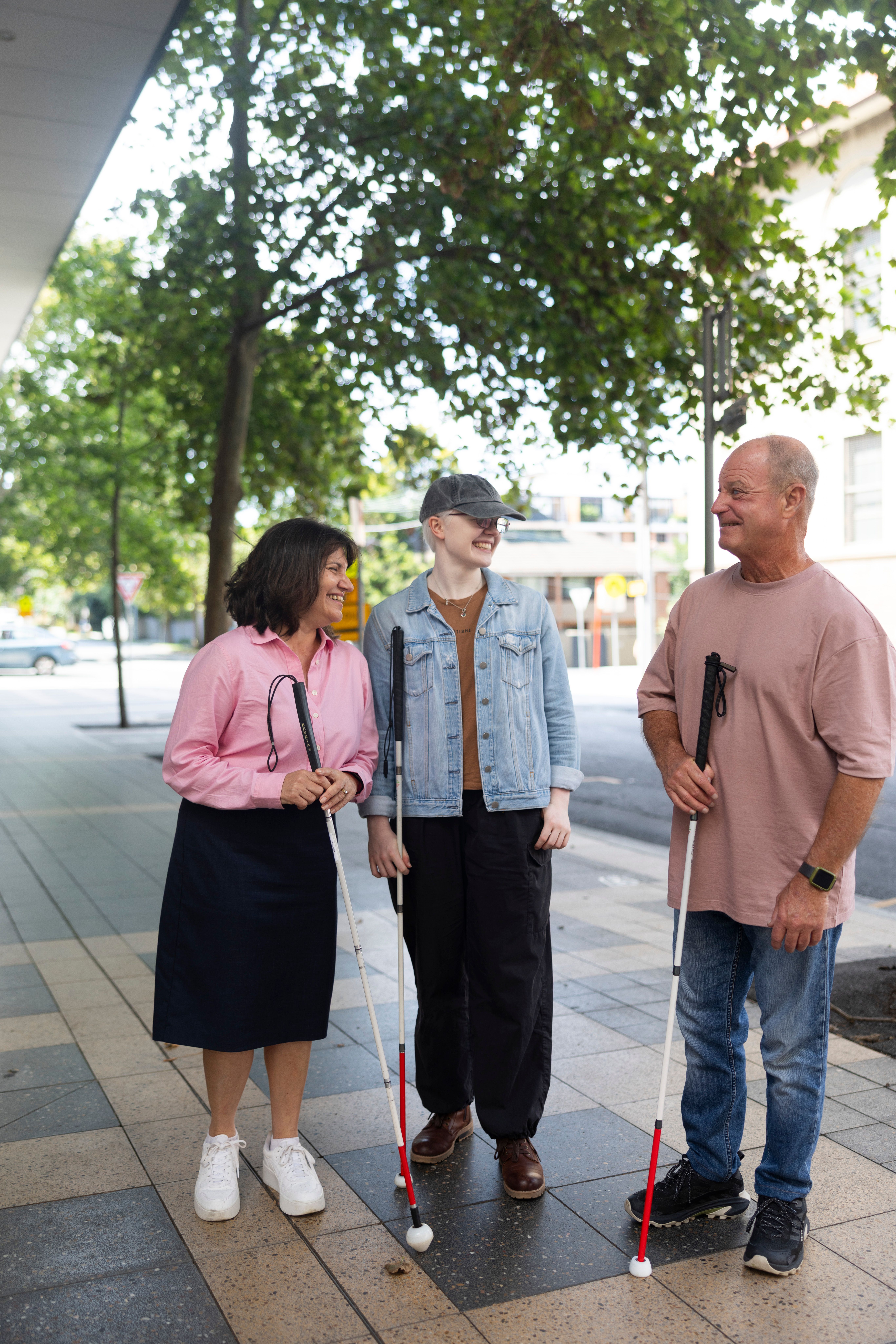 Three people standing and talking with white canes.