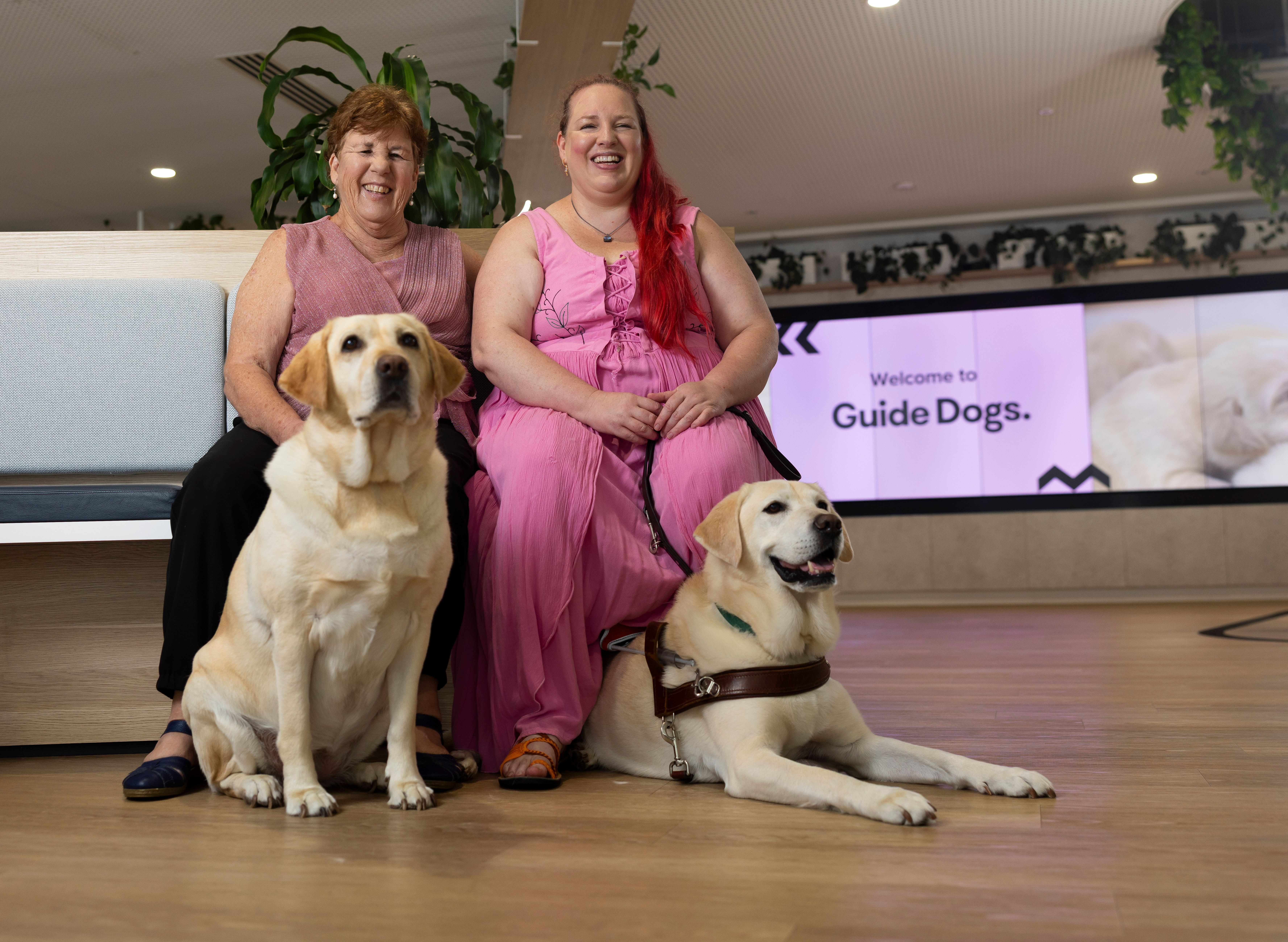Two people sitting together with their Guide Dogs.