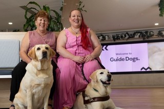 Two Guide Dogs Clients sitting with their yellow Labrador Guide Dogs.