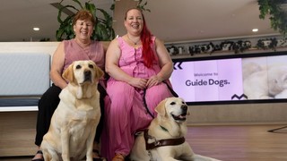 Two people sitting together with their Guide Dogs.