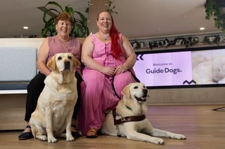 Two people sitting together with their Guide Dogs.