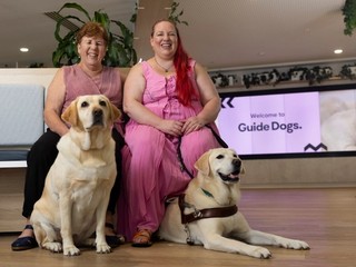 Two people sitting together with their Guide Dogs.