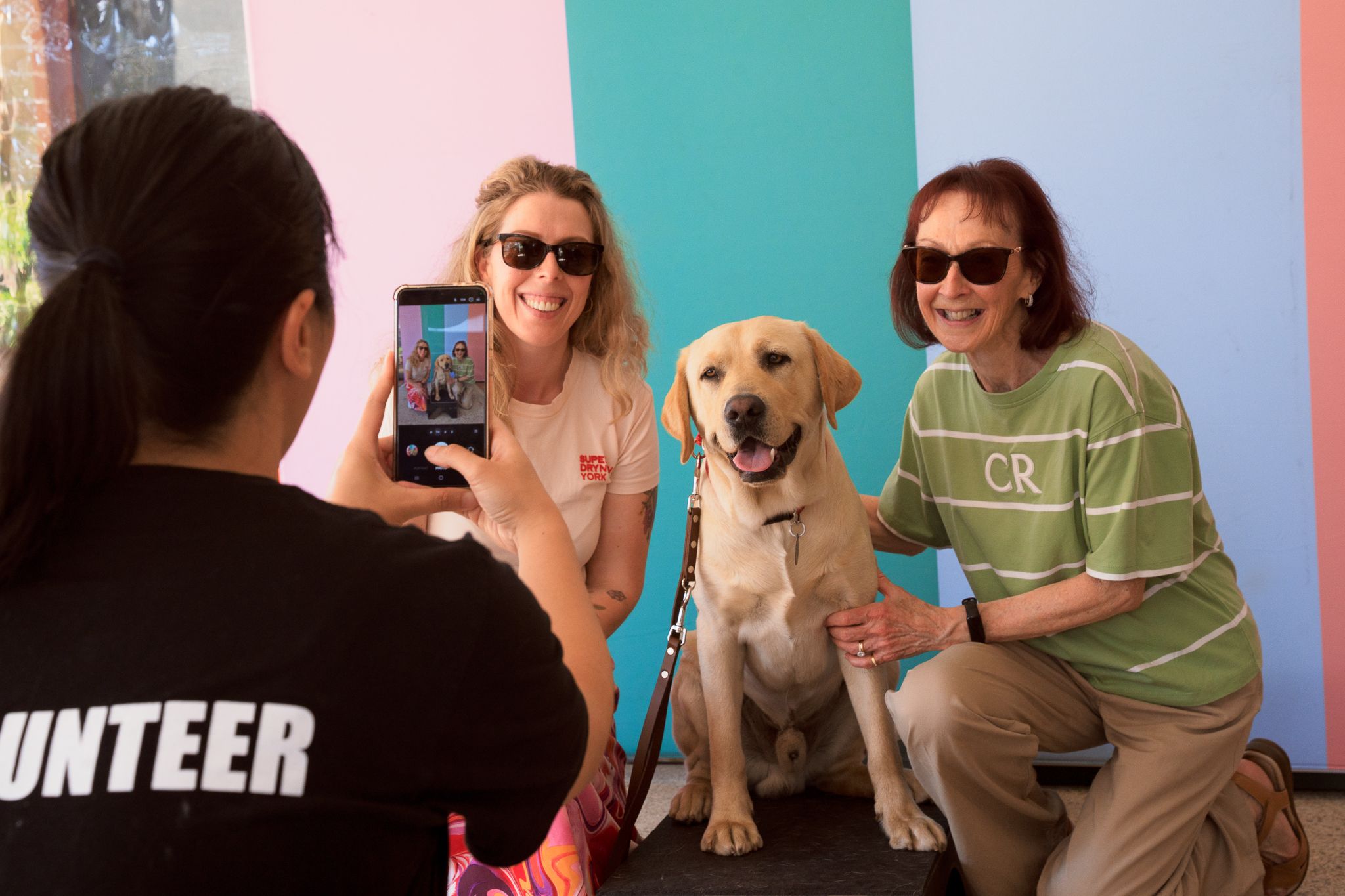 Two people posing for a photo with yellow Labrador Clifford.
