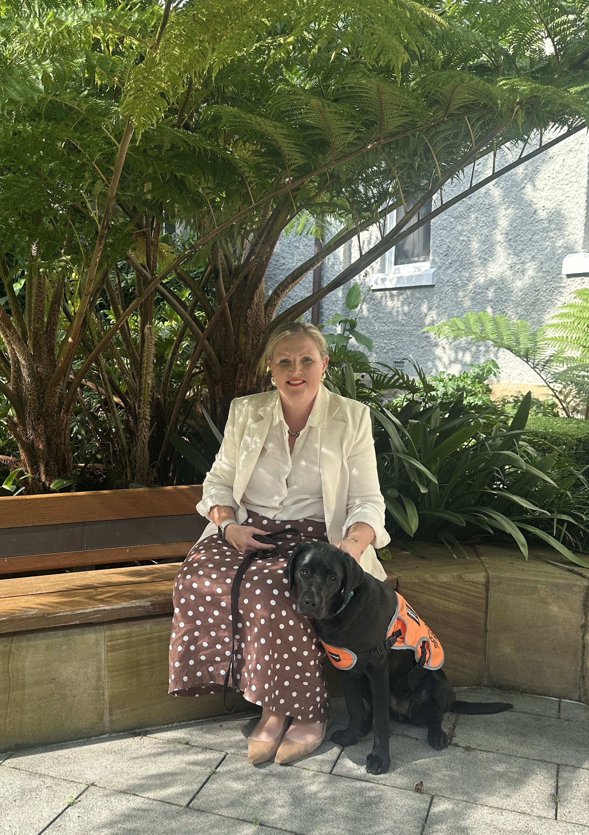 Allysia sitting with a black Labrador.