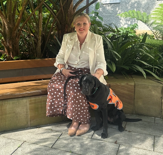 Allysia sitting with a black Labrador.