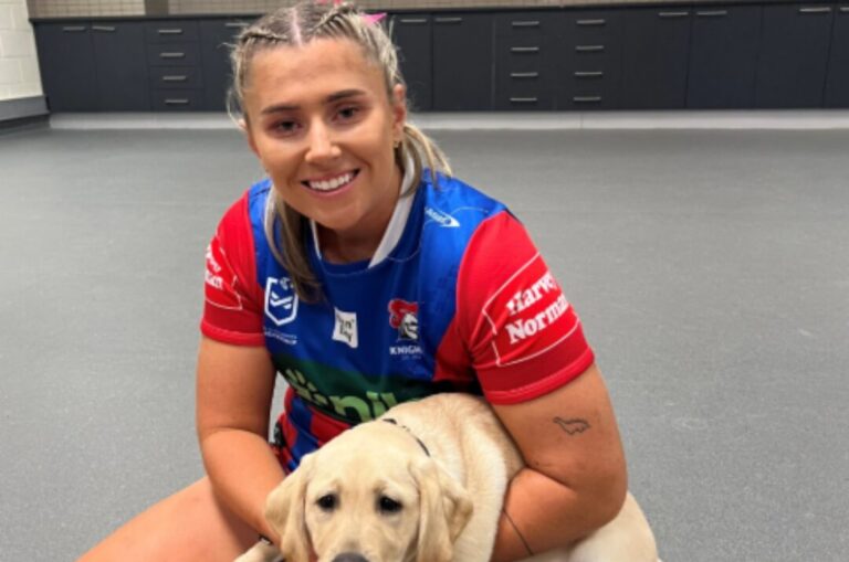Newcastle Knights player holding a yellow Labrador puppy.