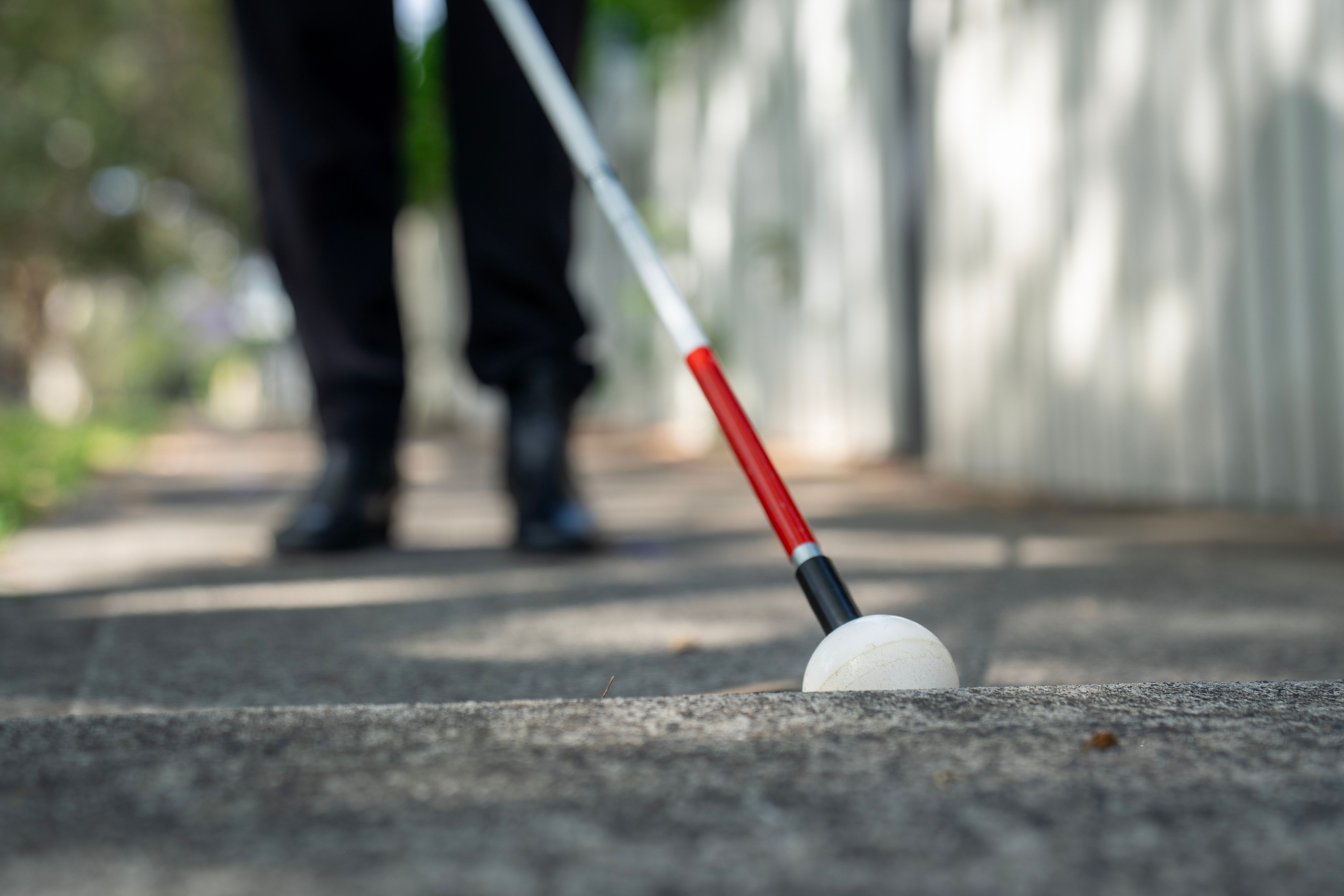 A close up of a cane of an uneven footpath.