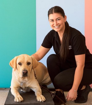 A person kneeling next to Clifford a yellow Labrador.