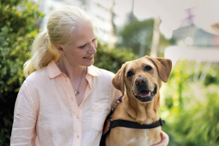 A Client smiling at her yellow Labrador Guide Dog.