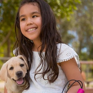 Sora sitting with a yellow Labrador puppy.