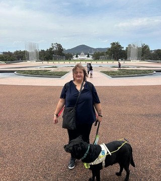 Lee standing with Guide Dog Frankie outside.