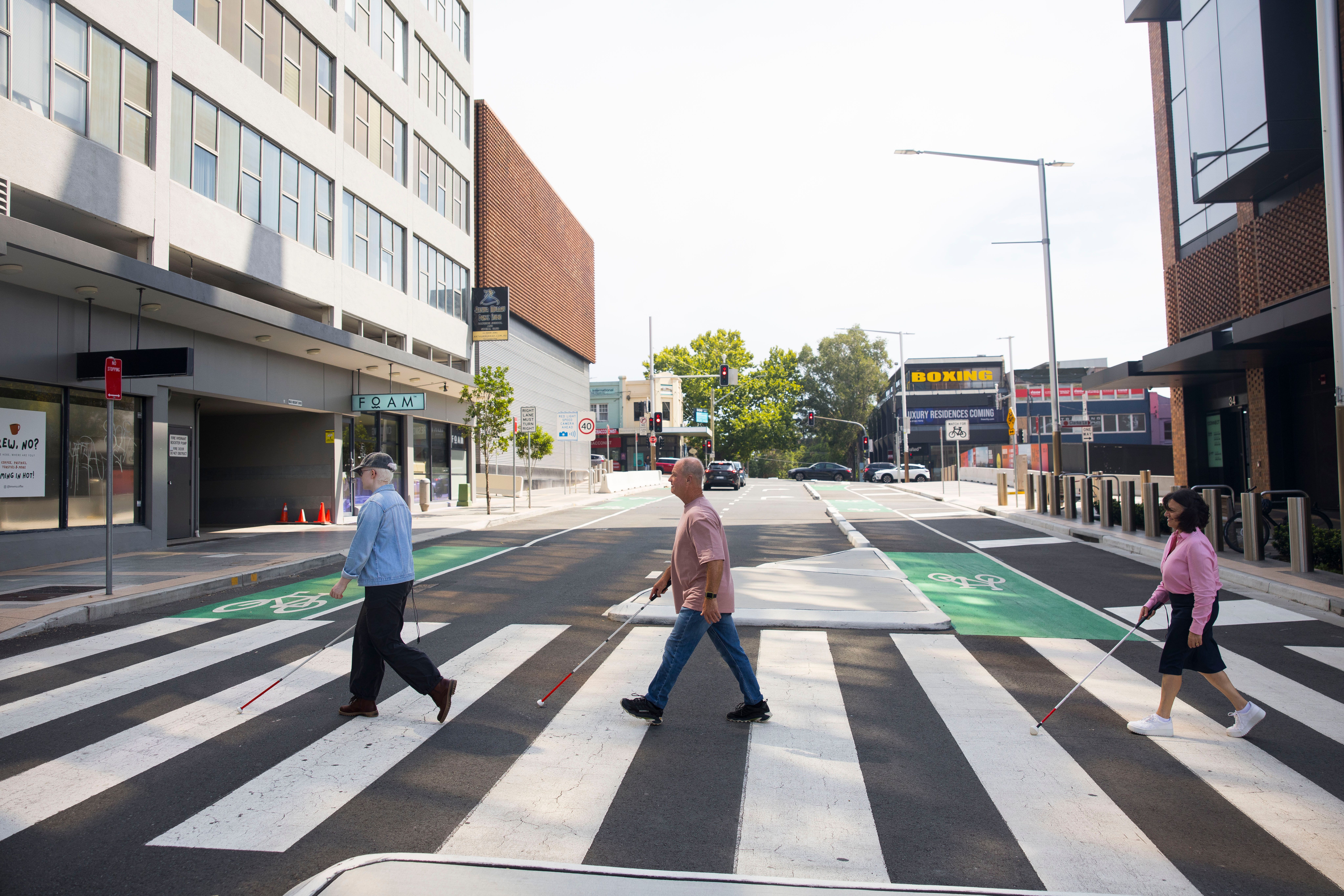 Two Clients walking across the road using their white canes.