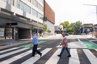 Two Clients walking across the road using their white canes.