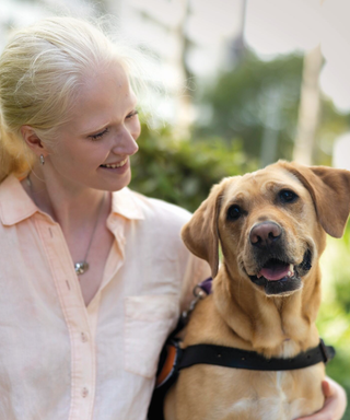 A woman sits outside with her yellow Labrador Guide Dog