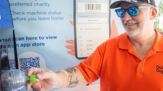 Tony putting a bottle into a kiosk.