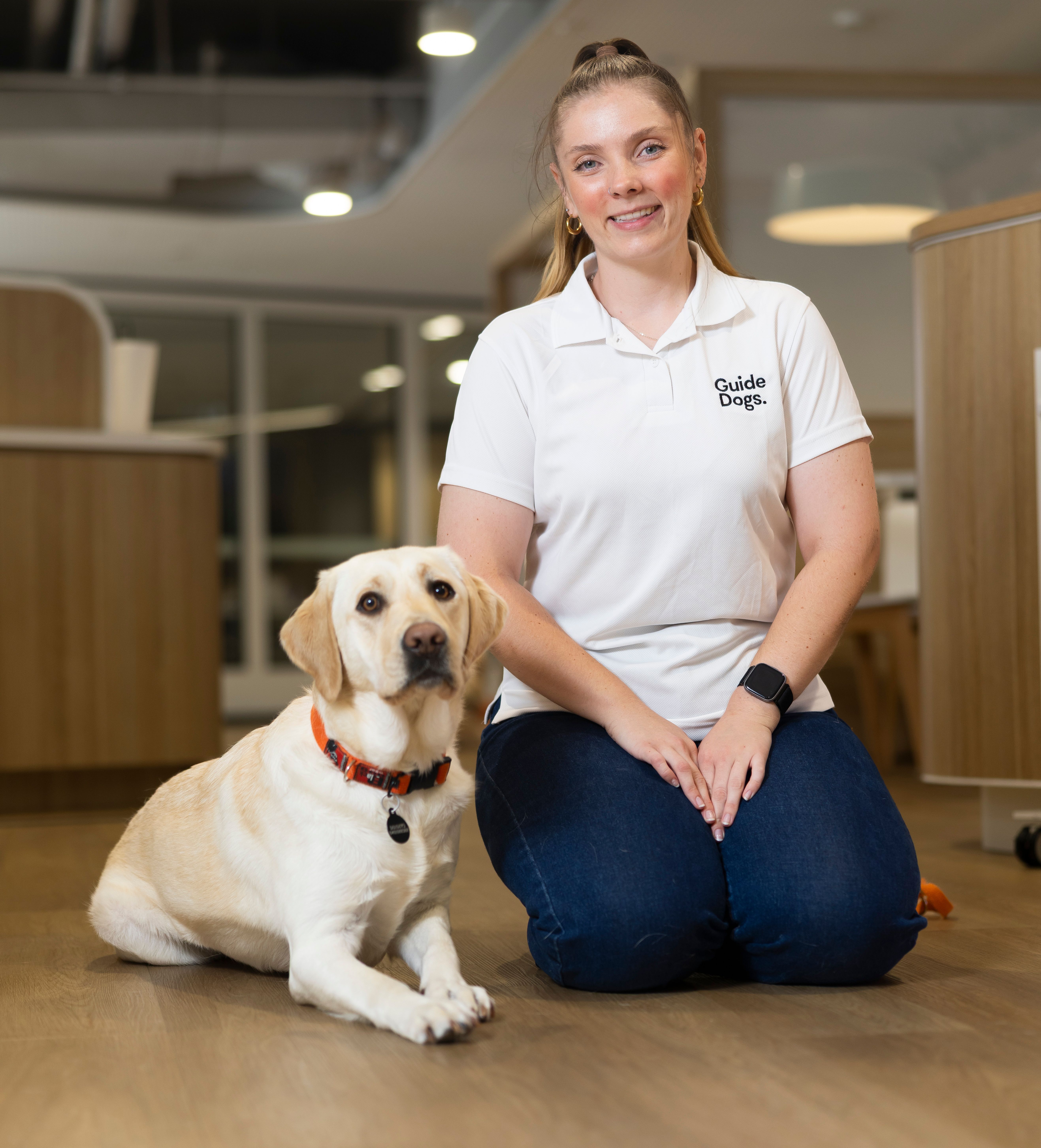 A person sitting next to a yellow Labrador. 