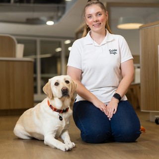 A person sitting next to a yellow Labrador.